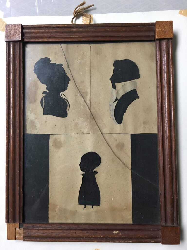 A wood framed set of three silhouettes, a woman, a man, and a baby